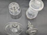 three clear glass vases with lids and lids sitting on a table