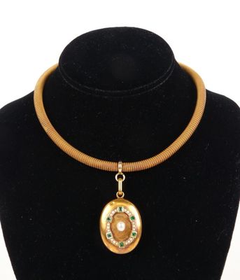 necklace with a gold and green pendant on a black mannequin
