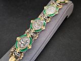 une photo d'un bracelet vert et doré posé sur un étui gris