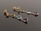 a pair of earrings with multi colored stones on a black surface