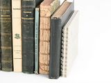 several old books are stacked on top of each other on a white surface