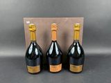 three bottles of champagne in front of a cardboard box