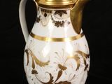 a white and gold coffee pot on a black background