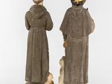 a pair of statues of a man and a woman with a dog