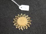 a close up of a gold sun medallion on a black surface