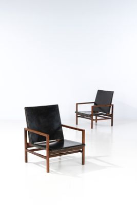 a pair of black leather lounge chairs in the style of person