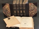 Plusieurs vieux livres sont posés sur une table, dont un est ouvert.