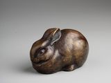 a small bronze sculpture of a rabbit on a white background