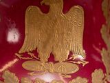 a red vase with a gold eagle on it