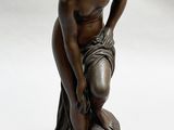 bronze statue of a woman kneeling on a rock with her hands on her knees
