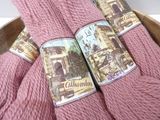 three skeins of pink yarn are in a wooden bowl