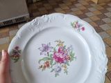 a person holding a plate with a floral design on it