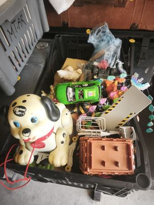 a toy dog sitting in a suitcase with other toys