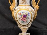 a white vase with gold trim and flowers on it