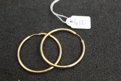 deux paires de boucles d'oreilles créoles en or posées sur une surface noire, accompagnées d'une étiquette de prix