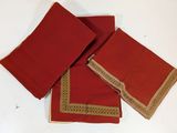 three red napkins with gold trims on a white table