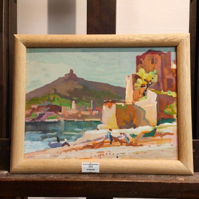 une peinture à l'huile représentant une scène de plage, dans un cadre en bois, posée sur une chaise