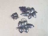 une broche en argent ornée de perles violettes, posée sur une table