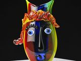 un vase coloré orné d'un visage, posé sur une table