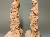 pair of sculptures of a woman and a man standing on a rock