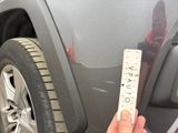 a hand that is holding a ruler in front of a car