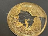 a gold plate with a picture of a bird on it
