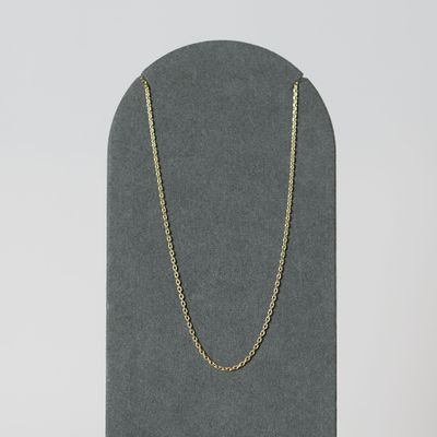 un collier à chaîne en or posé sur un présentoir noir