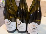 trois bouteilles de vin sont posées sur une table dans une pièce