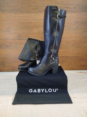 des bottes en cuir noir avec des fermetures éclair et un sac noir posé sur une table