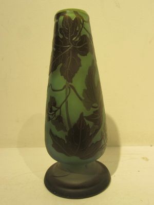 a green glass vase with a black base on a table