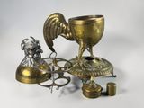 a golden cup with a rooster on it next to a candle holder