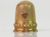 a gold thimble with a heart on it