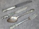 un service d'argenterie composé d'un couteau, d'une fourchette et d'une cuillère posés sur une table