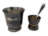 a silver cup and spoon sitting next to each other