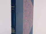 an old book with a blue cover sitting on top of a white table