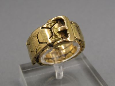 une image montrant un gros plan d'une bague en or posée sur une surface transparente