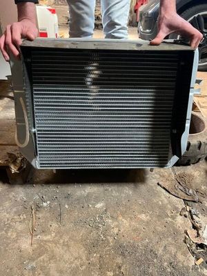 une photo d'un homme tenant un radiateur devant une voiture