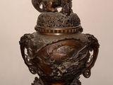 un vase en bronze orné d'un dragon, posé sur une table en bois