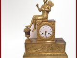une horloge en or avec une femme assise dessus
