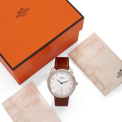 une boîte orange contenant une montre blanche avec un bracelet en cuir marron