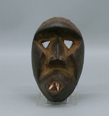 une image représentant un masque en bois posé sur un socle transparent