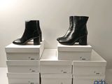 deux paires de bottines en cuir noir posées sur des cartons
