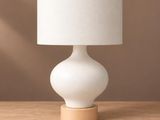 une lampe blanche posée sur une table en bois, près d'un mur marron