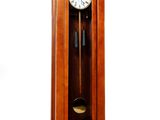une horloge de parquet en bois avec un pendule sur le côté