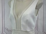 a white dress on a mannequin stand in front of a wall