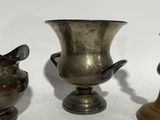 three silver vases sitting next to each other on a white surface