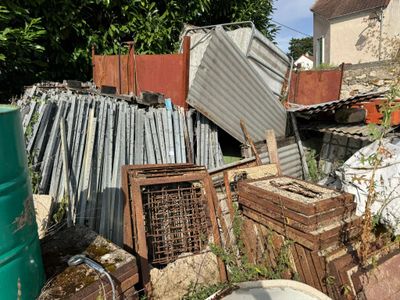 a pile of junk in the yard next to a trash can