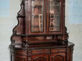 a wooden cabinet with a glass door in the corner of a room