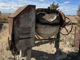 une bétonnière garée au milieu d'un champ de terre battue