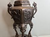 a bronze urn with a bird on top of it